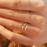 Close-up of 18K gold angel-wings heart necklace with sparkling lab diamond